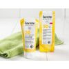 Αντηλιακή κρέμα με αντιγηραντική δράση SPF30 Lavera 50ml κίτρινη συσκευασία κρέμας με το κίτρινο κουτί και μια πράσινη πετσέτα στο φόντο