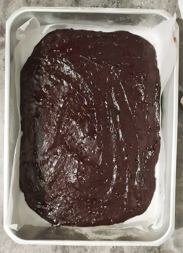 Η ζύμη του brownie απλωμένη στο ταψί έτοιμη για ψήσιμο