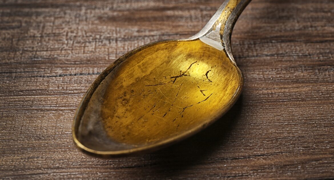 Ένα χάλκινο κουτάλι της σούπας με μουρουνέλαιο σε υγρή μορφή πάνω σε ξύλινη επιφάνεια